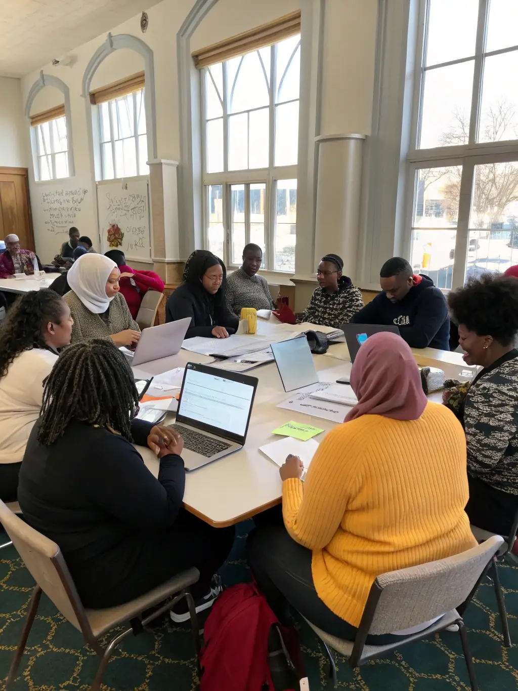 A photograph of a workshop session at a business conference in Durban, South Africa. Participants are working in small groups, brainstorming ideas and solving problems.